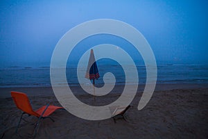 A view of an umbrella and two deckchairs on the beach during an unusual summer foggy morning