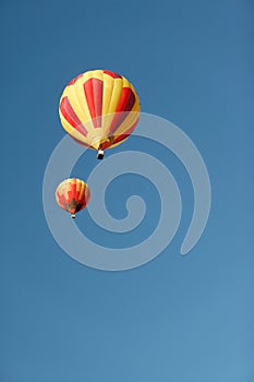 Two colorful hot air balloons against a blue sky.