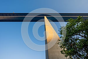 View up a pillar of the 136m tall Moseltal bridge at sunrise with tree in front