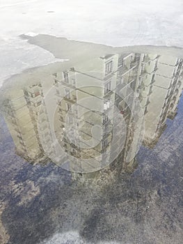 View of upside down building image in water puddle
