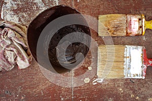 View of used paint brushes and the paint can over a wooden background