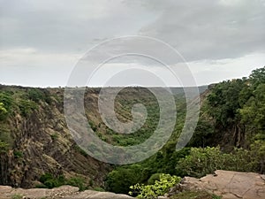 The view of a valley from a cliff with green forest and plants during monsoons in india