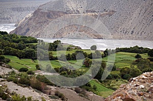View of a valley with green gardens on the banks of the Kali Gandaki River in the Kingdom of Upper Mustang in Nepal