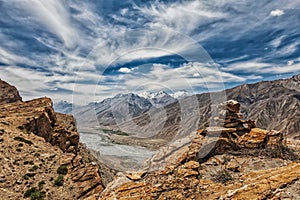 View of valley in Himalayas with stone cairn on cliff