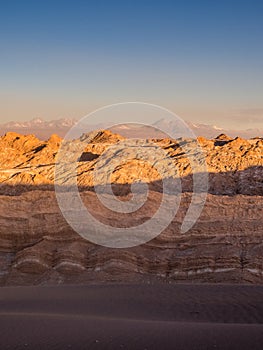 View of the Valley of the Moon in San Pedro de Atacama at sunset. In the background the volcano Licancabur and the Juriques