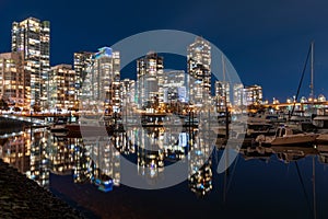 View of Vancouver downtown marina at night. Beautiful buildings skyline reflection on the water. Canada.