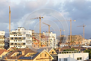 view of various cranes in a city, rooftops and buildings under construction. Speculation, industry