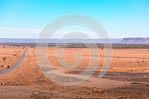 View of a vast semi-arid desert with a round running through it under a blue sky photo