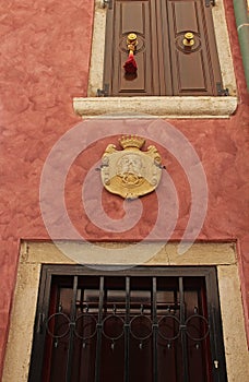 View of the Venetian facade of a house with a stone coat of arms with lions and a crown in the Mediterranean village of Rovinj,