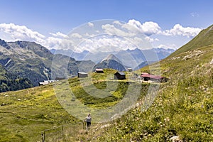 View of a very large and majestic alpine landscape in the Lord of the Rings style. In the foreground a girl walks toward