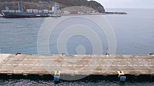 View from vessel deck of cruise ship pier and cargo port in distance near coast of Sint Maarten island