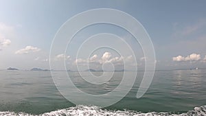 View video on a boat driving in the sea and splashing water Background island and clouds in the bright sky