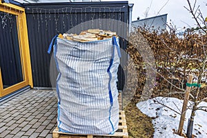 View of the villa grounds with birch firewood bundled in transport bags on pallets.