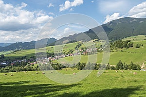 View on village Liptovska Luzna at the foothills of Low Tatras mountains with lush green meadow, forested hills and