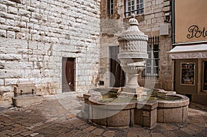 View of wall, fountain and shop in Vence.