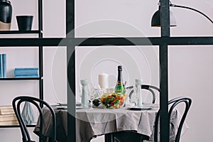View through the wall with muntins on elegant dining room table covered with grey tablecloth