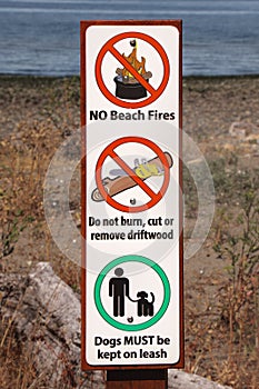 View of sign No beach Fires, Do not burn, cut or remove driftwood, Dogs Must be kept on leash on Kin Beach Provincial Park in photo