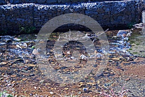 SHALLOW WATER FILTERING THROUGH A STAUNCH WALL photo
