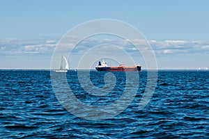 A view from the water of the Gulf of Finland on a summer day, cargo ships and yachts are sailing in the distance, blue