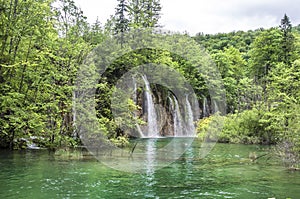 View of waterfalls with turquoise water and green trees in Plitvice Lakes National Park in summer, Croatia