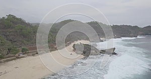 View of the waves crashing against a flying reef over a white sand beach under a hill, raw footage, ungraded, no color, log