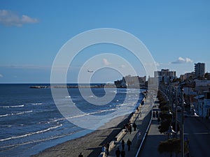 View of the waves in the Mediterranean Sea with buildings during winter at the beach in Larnaka with plane