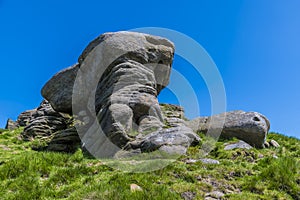 A view of a weathered millstone monolith at the top of the path leading to the escarpment of Stanage Edge in the Peak District, UK