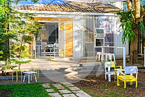 View of the well designed patio area with wooden chairs in the backyard of modern design house.