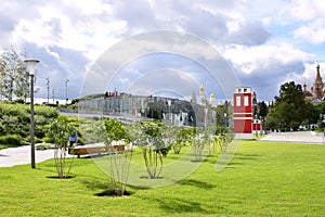 View of a well-groomed lawn with lilac bushes and a bright red building in Zaryadye Park