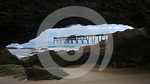 view of a wharf from inside a cave on a beach at catherine hill bay