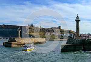 View of Whitby harbor entrance with a sailing boat, on the northeast coast of Yorkshire