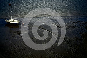 View of white boat stranded at the low tide of river Thames banks in the evening