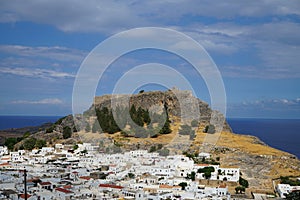 View of the white buildings of Captains houses of the 16th-18th centuries and the ancient Acropolis of Lindos in August.