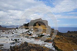 View of the white buildings of Captains houses of the 16th-18th centuries and the ancient Acropolis of Lindos in August.