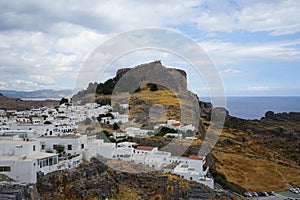 View of the white buildings of Captains houses of the 16th-18th centuries and the ancient Acropolis of Lindos in August.