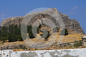 View of the white buildings of Captains houses of the 16th-18th centuries and the ancient Acropolis of Lindos in August.
