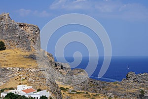 View of the white buildings of Captains houses of the 16th-18th centuries and the ancient Acropolis of Lindos in August.