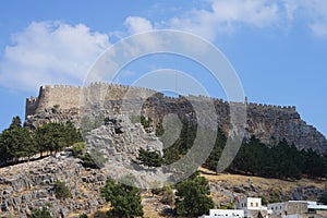 View of the white buildings of Captains houses of the 16th-18th centuries and the ancient Acropolis of Lindos in August.