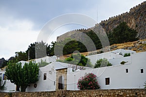 View of the white buildings of Captains houses of the 16th-18th centuries and the ancient Acropolis of Lindos in August. Rhodes