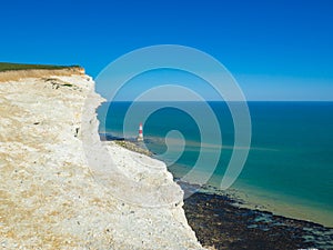 View of the white chalk headland cliffs and Beachy Head Lighthouse in the Seven Sisters National park, Eastbourne, England.