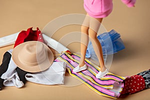 View on white female doll legs next to big clothes mess on a floor