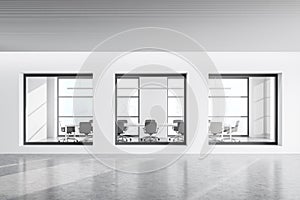 View of white office corridor with three meeting room windows