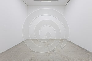 A view of a white painted interior of an empty room or an art gallery with a fluorescent lighting and wood floors