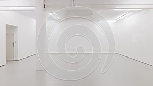 A view of a white painted interior of an empty room or an art gallery with a skylight lighting and concrete floors photo