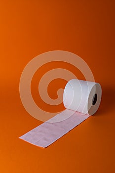 View of a white toilet paper roll over an orange background photo