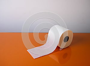 View of a white toilet paper roll over an orange background photo
