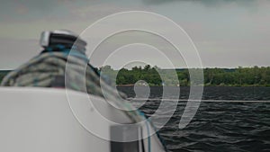 View from white yacht sideways to the wooded shore and the overcast sky