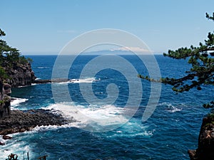 View of wild rocky coast, the pacific ocean and an inhabited volcanic island over the horizon