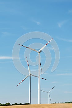 View of a wind power plant on a background of blue sky and fields with grain crops. The concept of environmental electricity produ