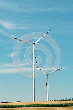 View of a wind power plant on a background of blue sky and fields with grain crops. The concept of environmental electricity produ